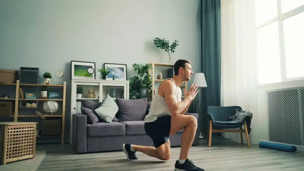 A man performs a forward lunge exercise in a living room.