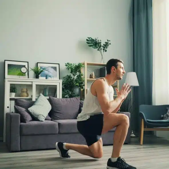 A man performs a forward lunge exercise in a living room.