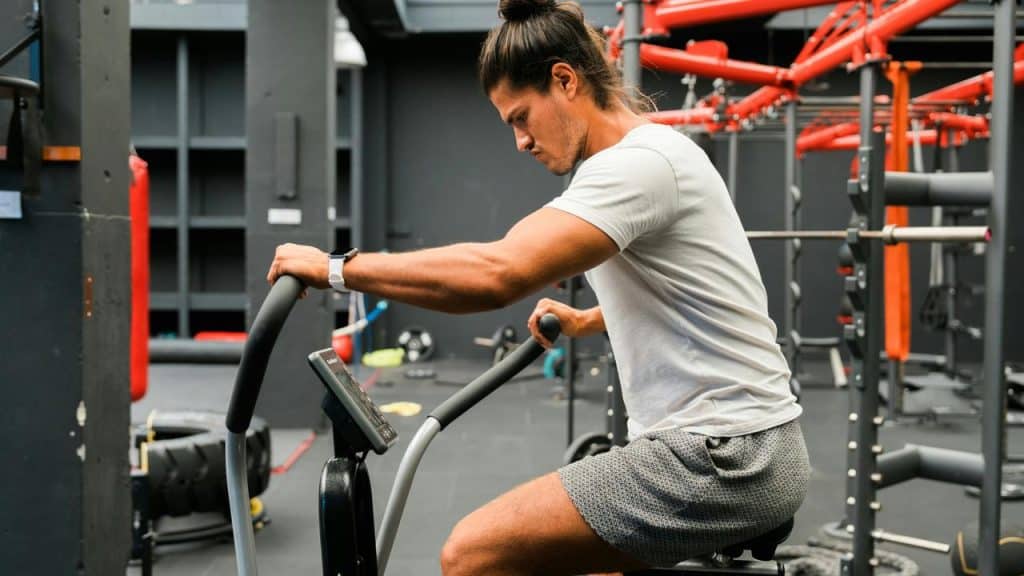 A man pedals a stationary exercise bike in a gym weight room.