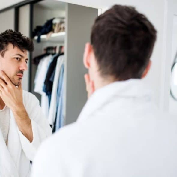 A man looking into a mirror with calm determination.