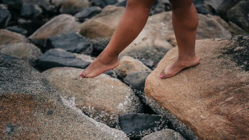A person crossing from one stone to another.