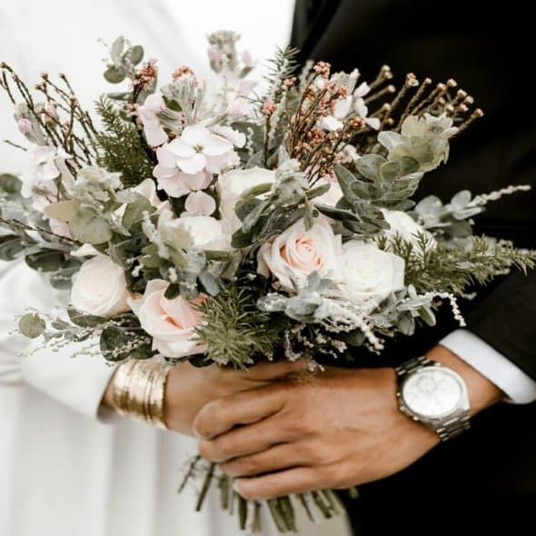 Bride and groom holding wedding bouquet.