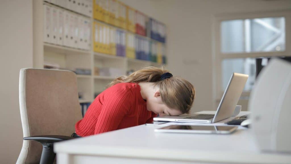 A woman sleeping on her laptop.