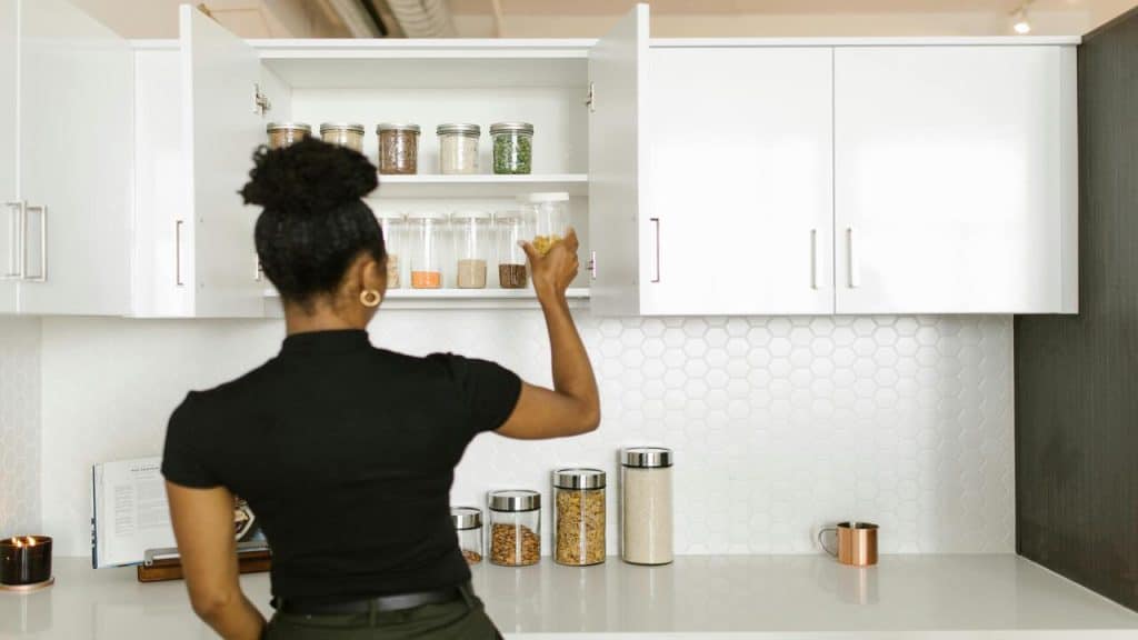 A woman taking stuff out of the pantry.