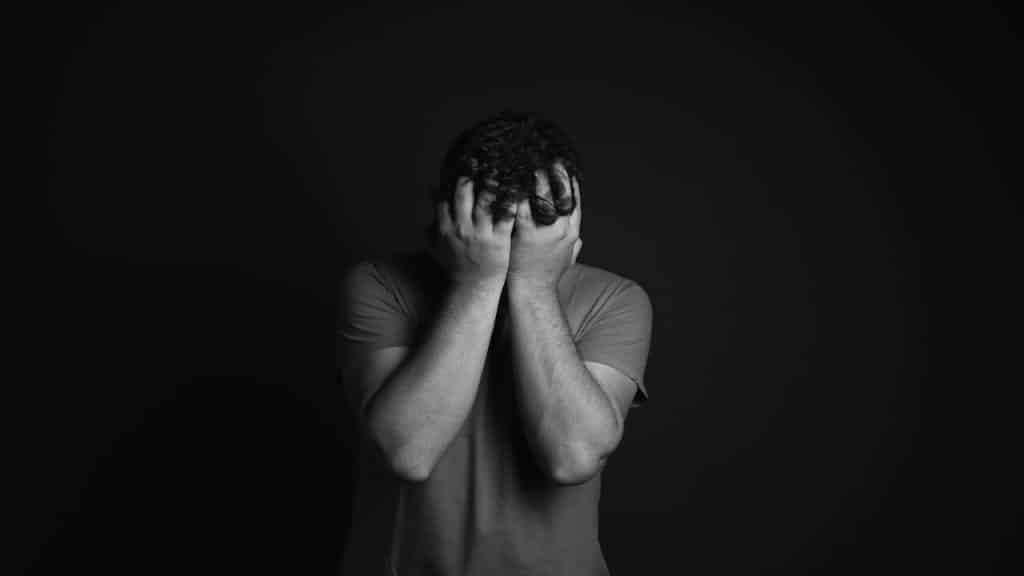 A man covering his face with his hands.