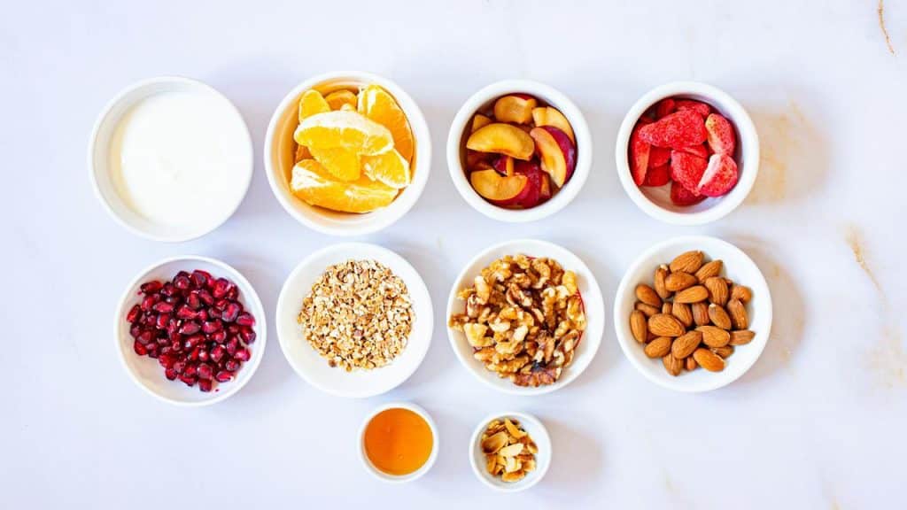 A selection of small bowls with fruit, nuts, oats, yogurt, and honey.