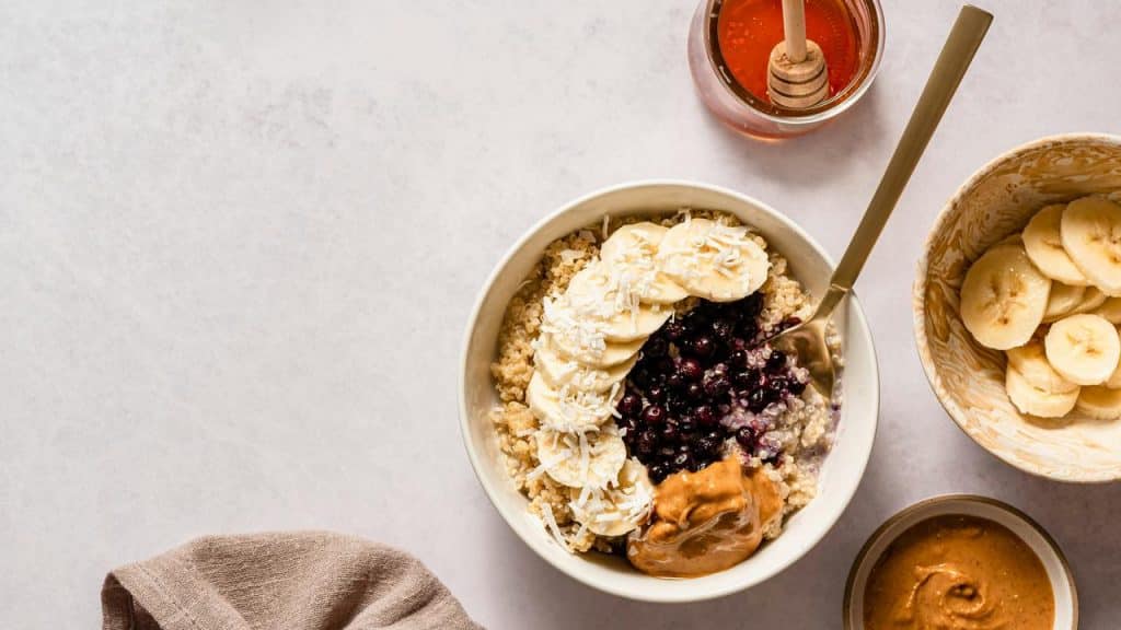 A bowl of porridge topped with banana, blueberries, and peanut butter.