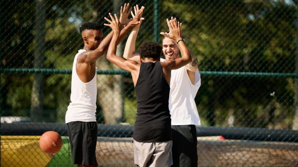 A trio of basketball players high-fiving on an outdoor court.