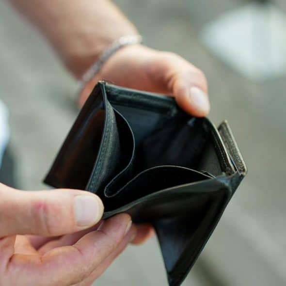 A pair of hands holding an open, empty black wallet.