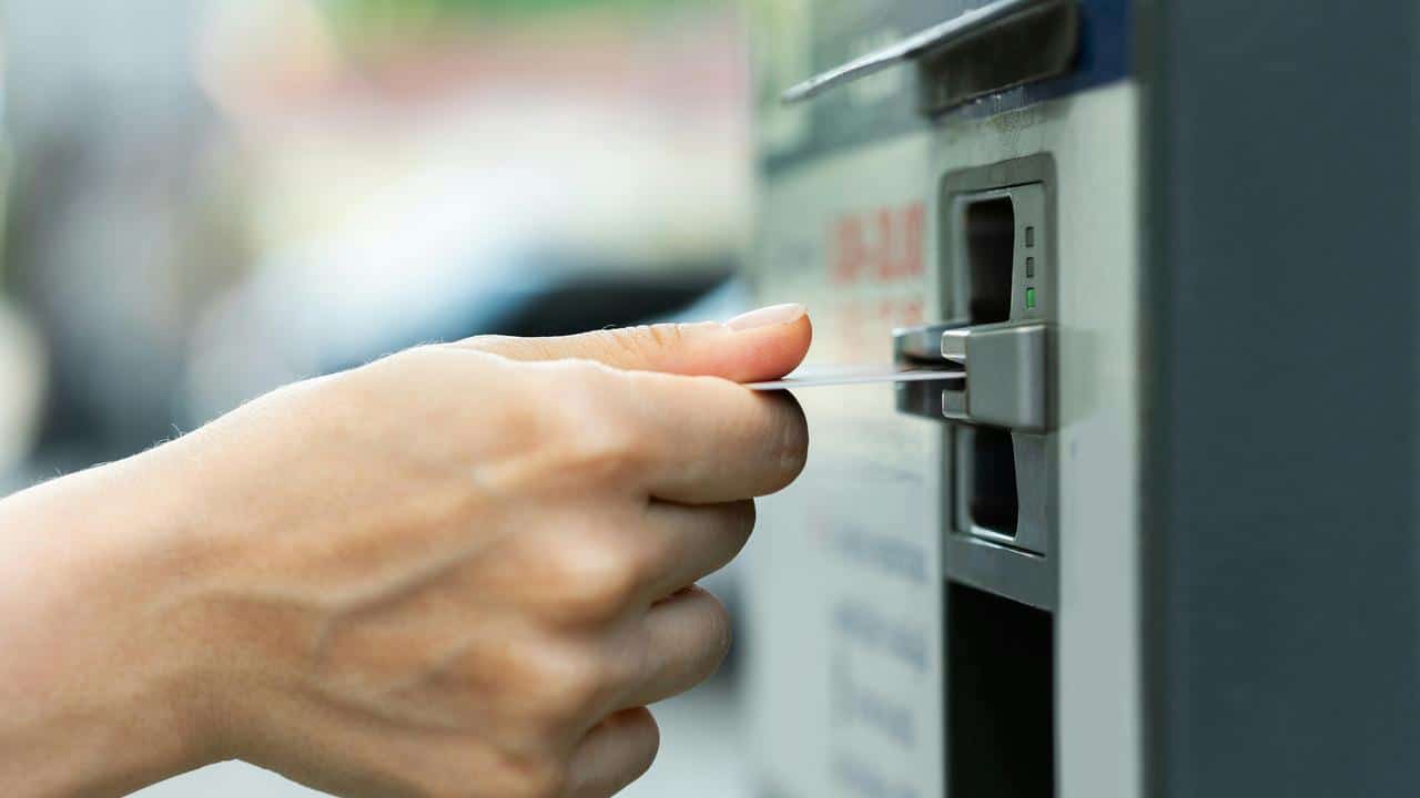 A hand inserting a card into an ATM’s card slot.