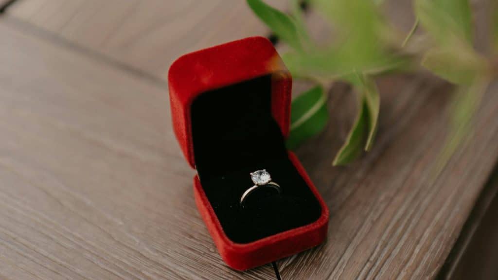 A diamond engagement ring in an open red velvet box..