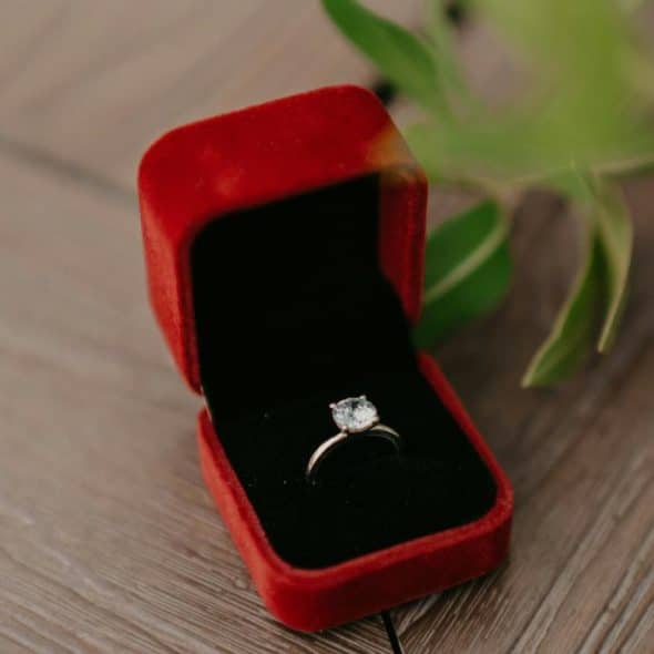 A diamond engagement ring in an open red velvet box..