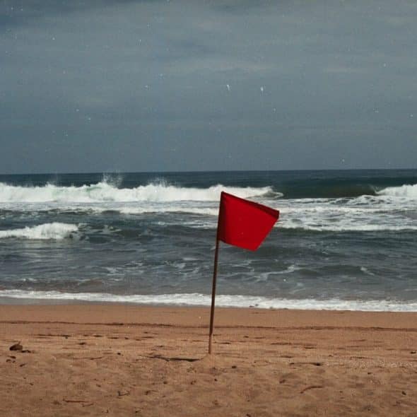 A red flag sticking out of the sand