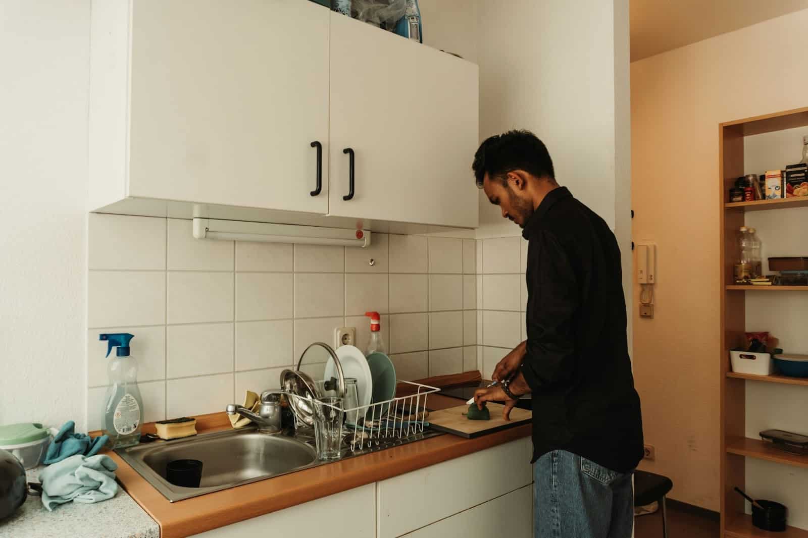 A man in the kitchen doing a chore.