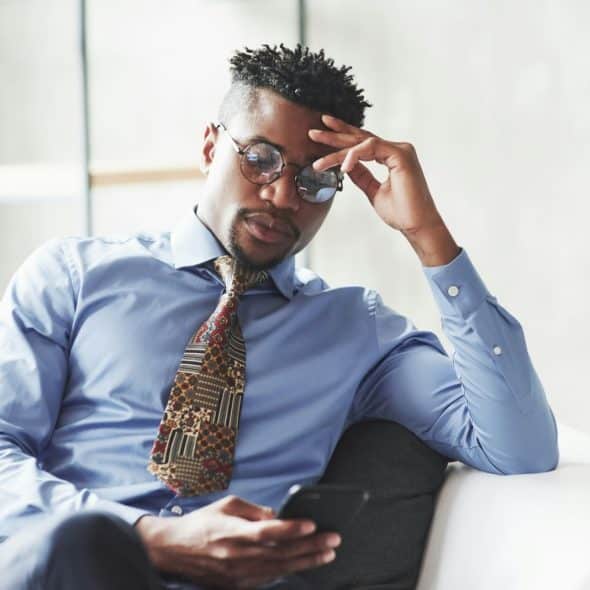 A man looking serious while using a mobile phone