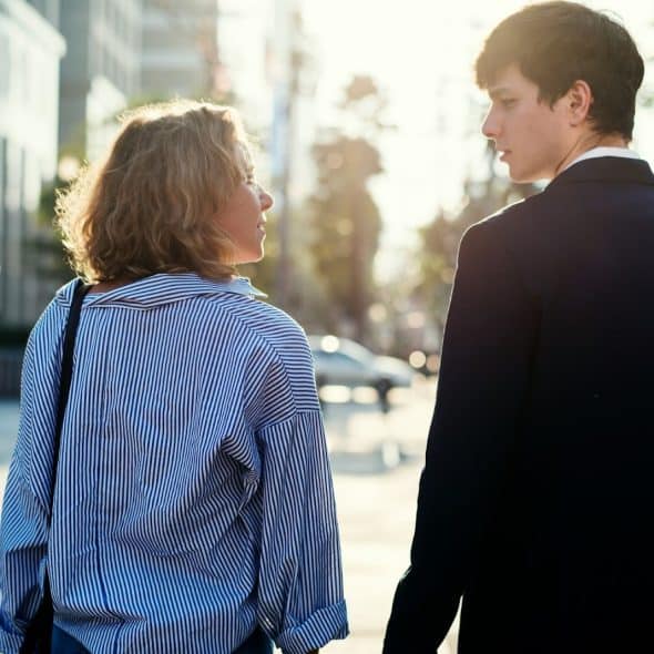 A man looking at the woman while walking outside