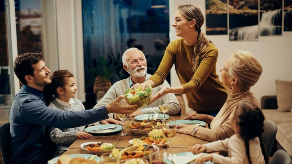 A happy family of various ages is sharing a meal around a dinner table.