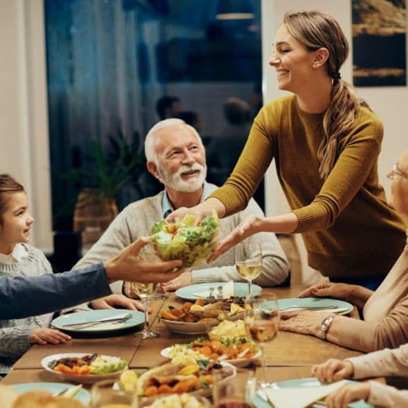 A happy family of various ages is sharing a meal around a dinner table.