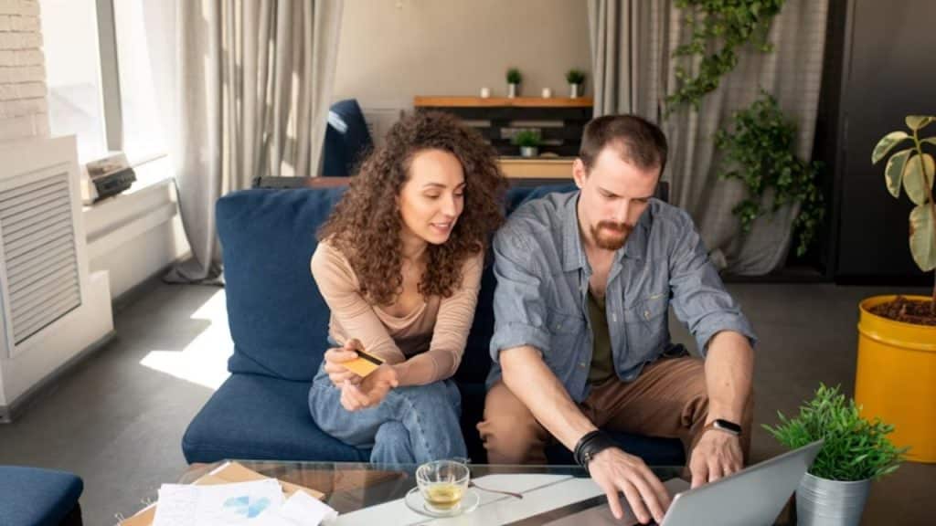 Couple sitting in the living room, discussing finances with a laptop