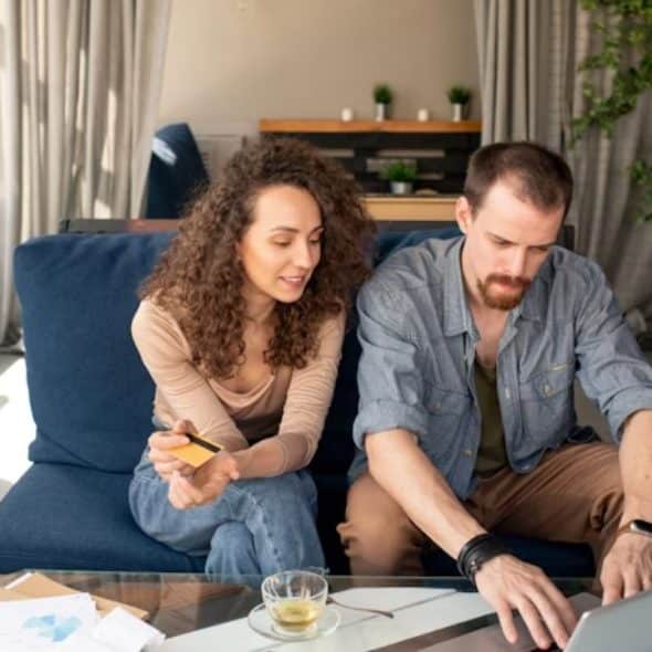 Couple sitting in the living room, discussing finances with a laptop