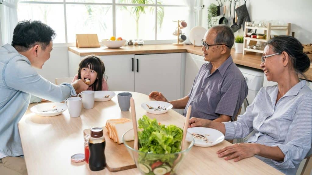 A multi-generational Asian family is eating a meal together in a kitchen.