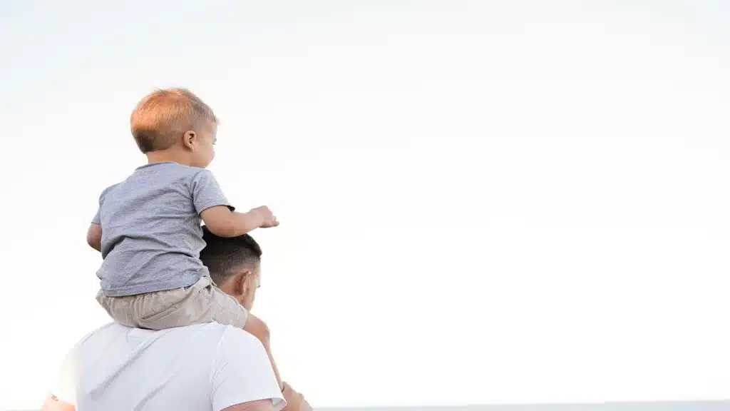 A dad carrying his child on his shoulders.