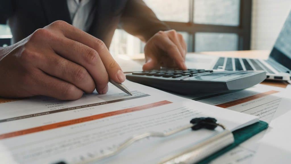 A person using a calculator and pen over financial documents.