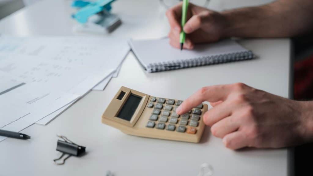 A calculator on a desk over financial charts with a notebook nearby.