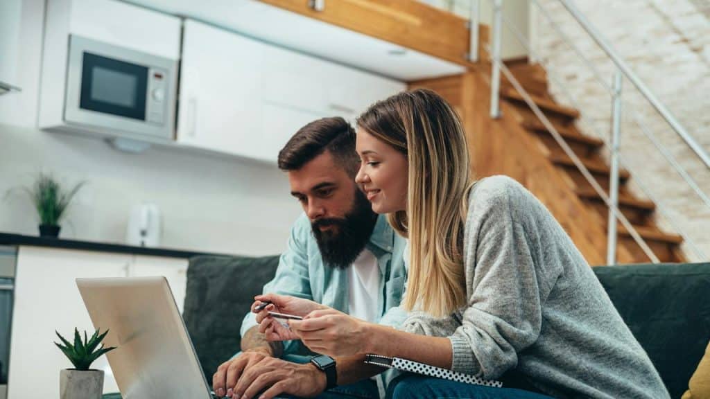 A couple on a couch using a laptop, one holding a credit card.