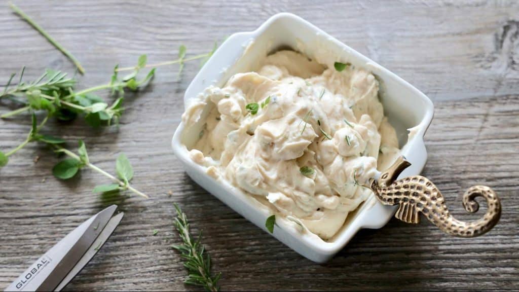A dish of creamy cottage cheese garnished with fresh herbs.