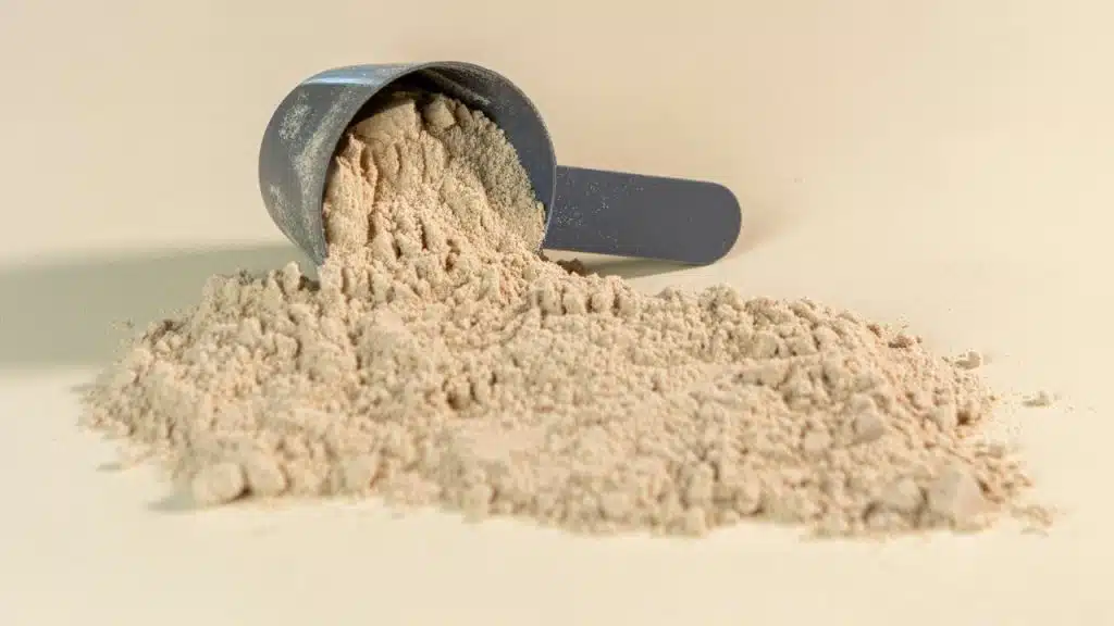 A scoop of protein powder spilled on a surface.