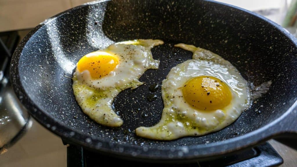A skillet with two sunny-side-up eggs cooking.