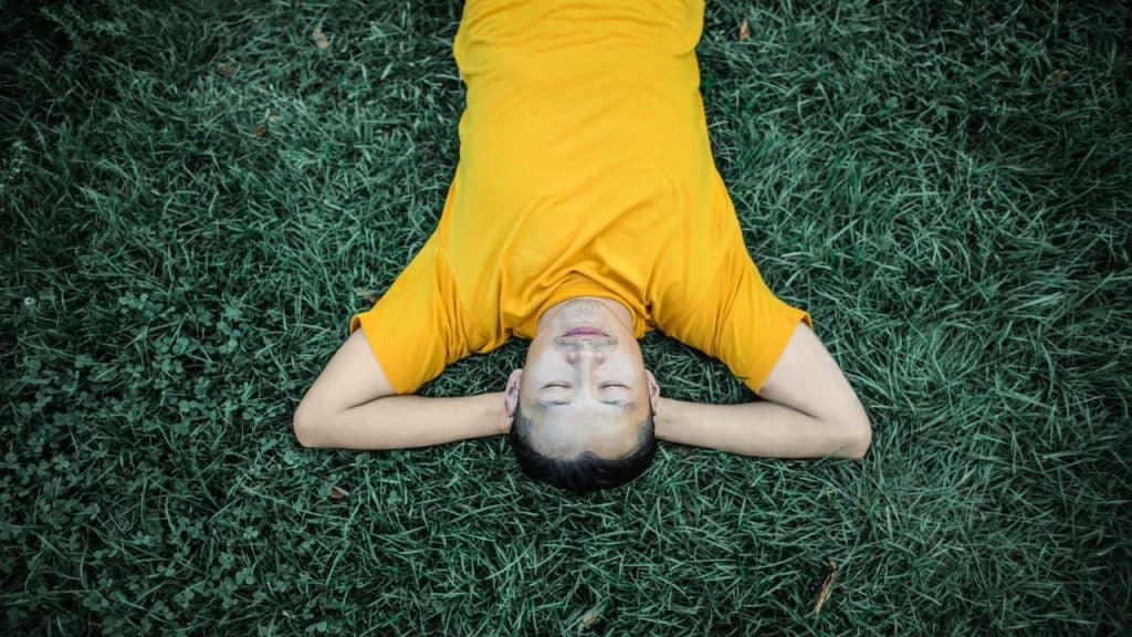 A man laying on grass and sleeping