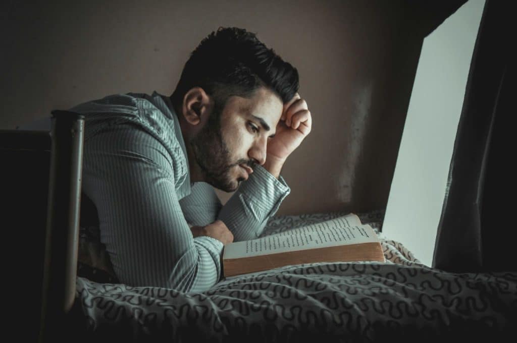 A man looking tired while reading a book