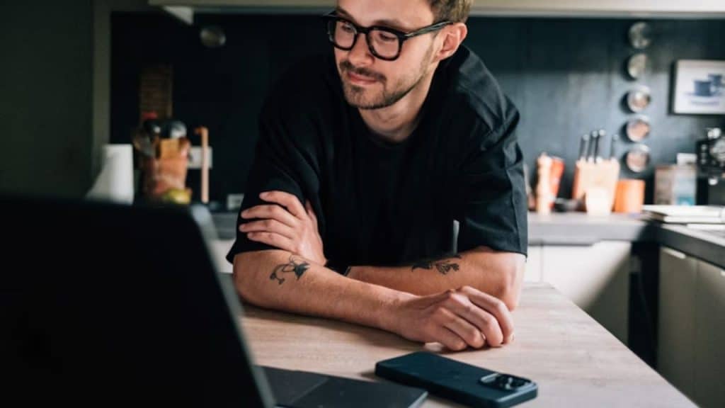 Man forcing a smile during a video call from a small apartment.