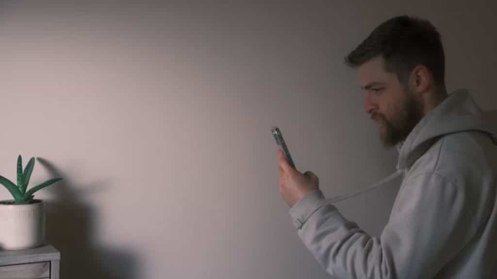 Man looking at social media photos, appearing concerned.