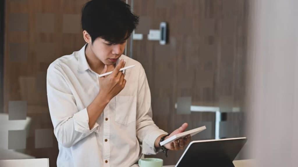Man journaling with a thoughtful look at a café.