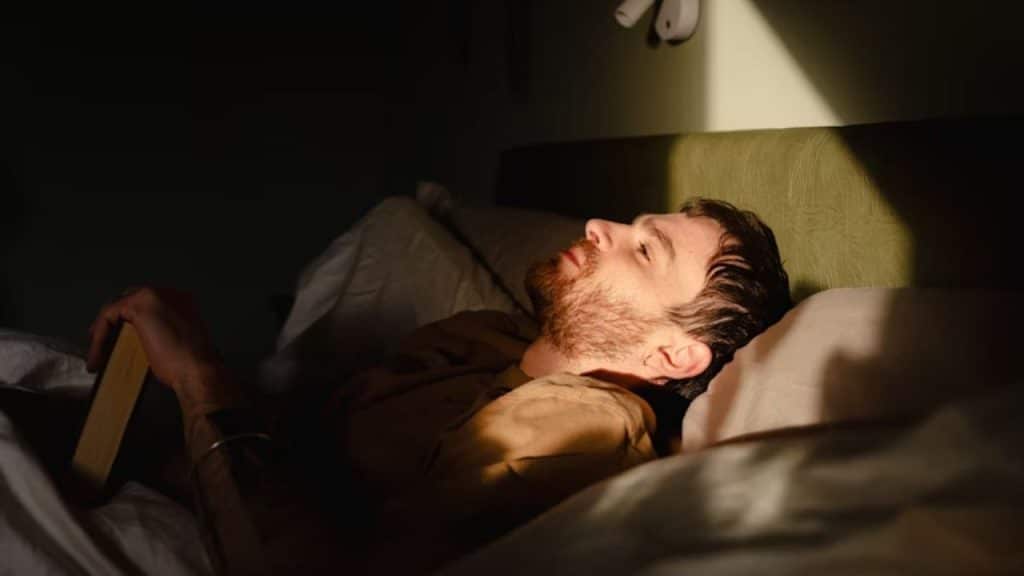 Man lying awake in bed, looking up at the ceiling.