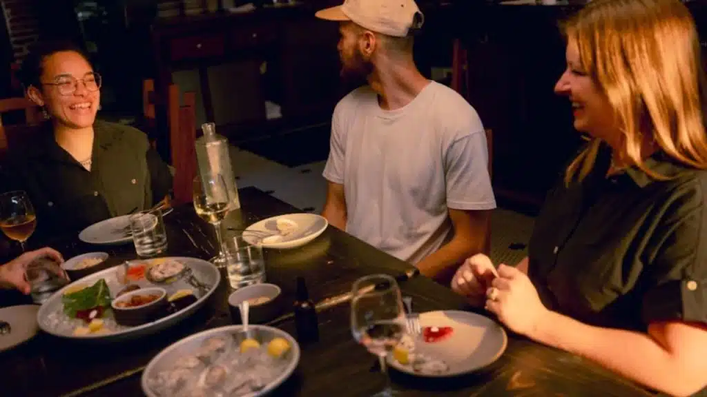 Man at a table with friends, feeling isolated from the conversation.