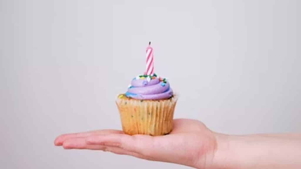A Hand with a cupcake and a candle.