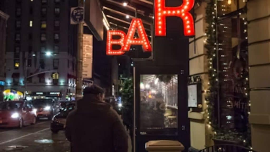Man standing outside a bar, debating whether to go in.