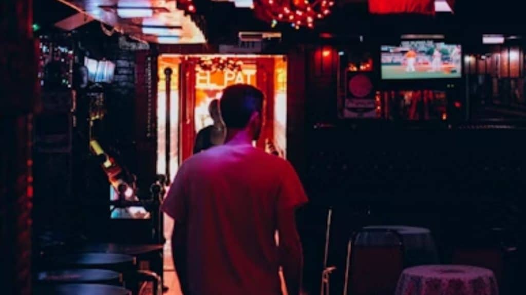 Man exiting a bar alone early in the evening.