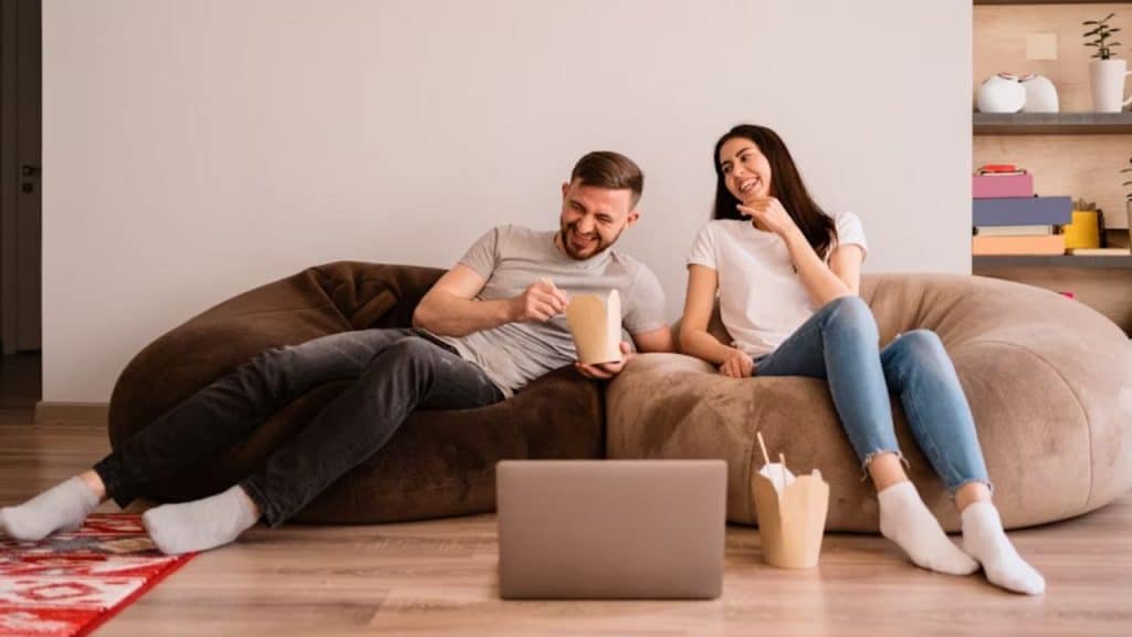 Couple sitting and eating on the couch having a warm, honest conversation.