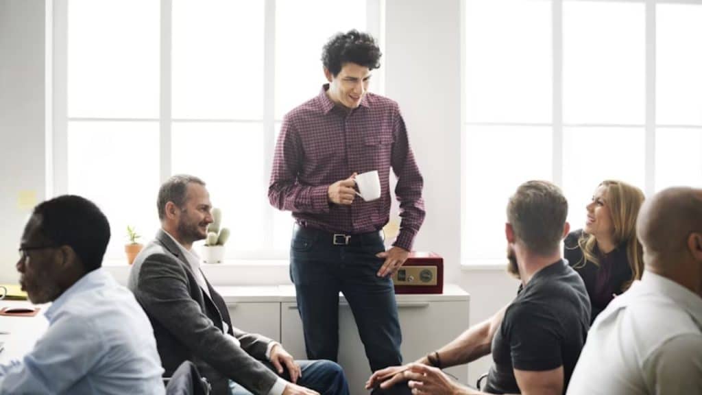Man chatting with coworkers at the office, looking respected and composed.