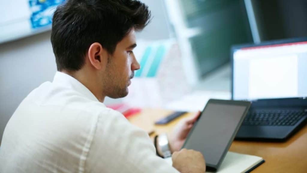 Man working at computer, visibly distracted by messages.