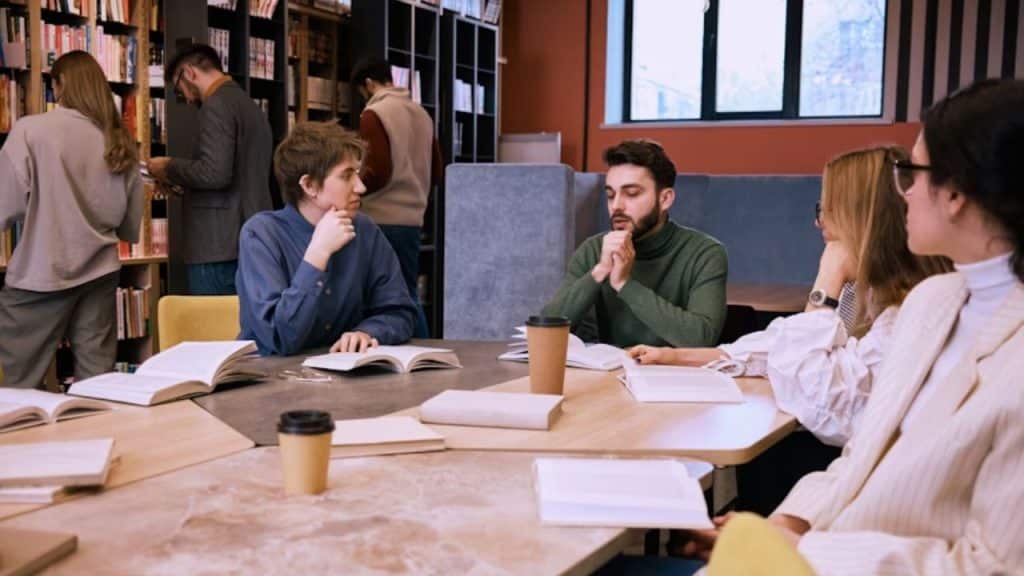 Group of colleagues in a meeting with subtle tension and curiosity.