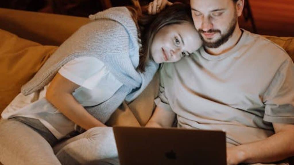 Man working while sitting with his supportive partner on the couch.
