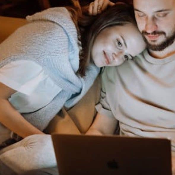Man working while sitting with his supportive partner on the couch.