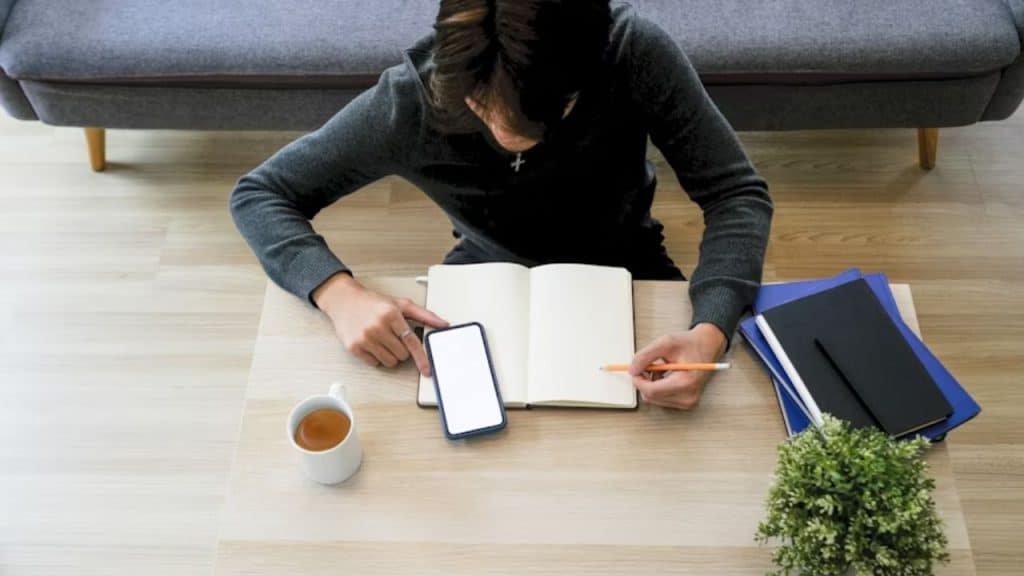 Man writing personal goals in a journal over morning tea.