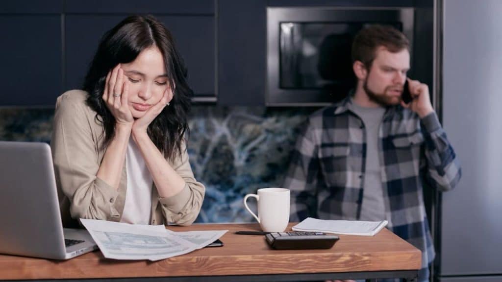 Man distracted by work call while partner looks disappointed.